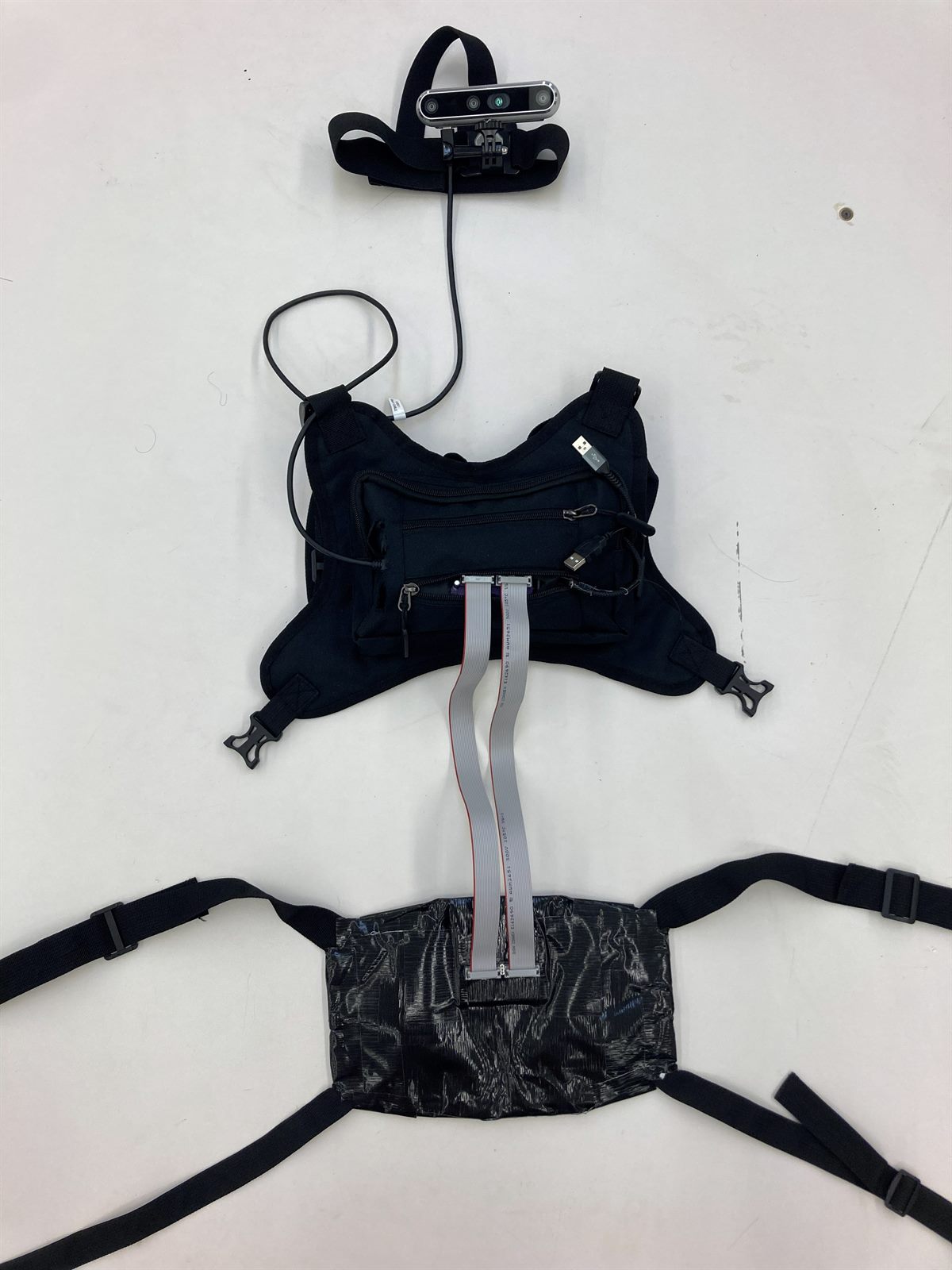 The complete wearable rig laid out: head-mounted stereo camera, harness, and haptic belt